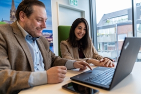 BMWK/ Mittelstand-Digital Ein Mann und eine Frau im Gespräch vor einem Laptop.