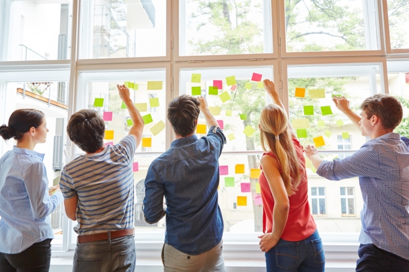Fünf Personen kleben Post-its an ein Fenster